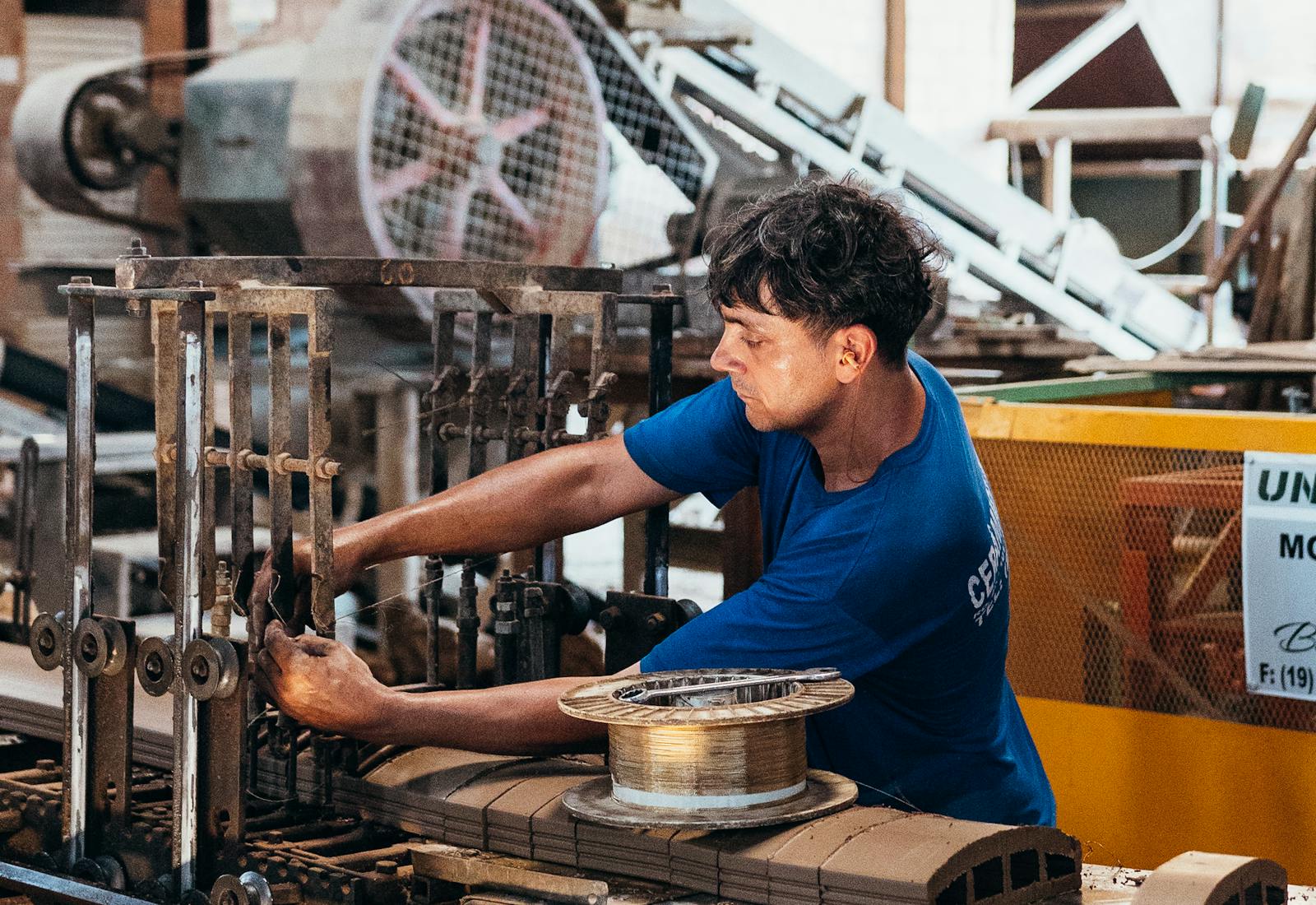 Operatore industriale a bordo linea durante il setup di una macchina di produzione